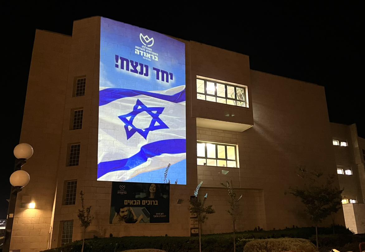 בניין המכללה מואר בדגל ישראל עם הכיתוב "יחד ננצח"